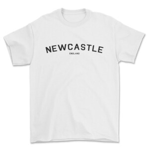 May include: White t-shirt with black text that reads "NEWCASTLE ENGLAND" in a curved arch.