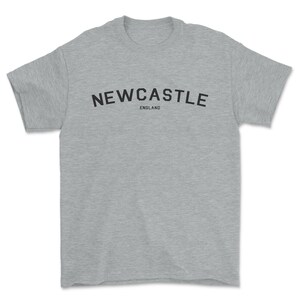 May include: A heather gray t-shirt with black text that reads "NEWCASTLE ENGLAND".