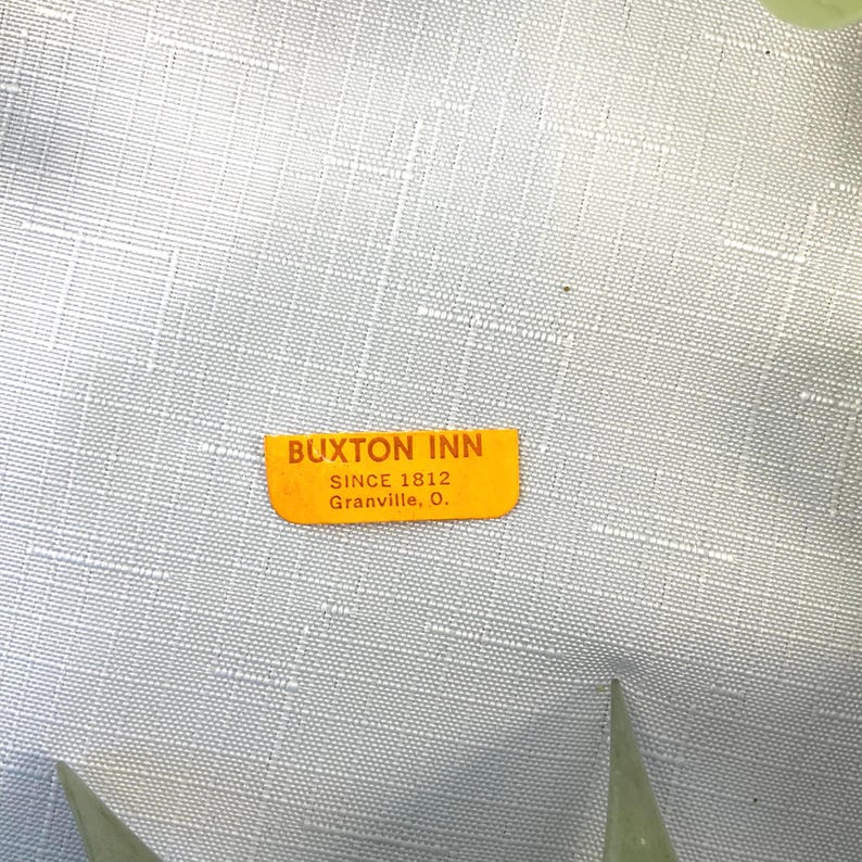 K&ouml;nnte beinhalten: Ein orangefarbener Buxton Inn-Aufkleber mit dem Text "BUXTON INN SINCE 1812 Granville, O." wird vor einem hellgrauen, strukturierten Hintergrund angezeigt. Der Aufkleber ist rechteckig mit abgerundeten Ecken.