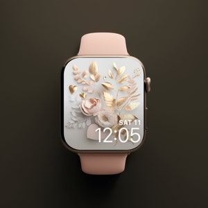 May include: A pink and gold smartwatch with a floral design and the time 12:05 displayed on the screen. The screen also shows the date, SAT 11.