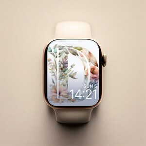 May include: A white Apple Watch with a gold band and a floral watch face. The watch face features a watercolour floral design with the letter "D" in the centre. The time is 14:21 and the date is SUN 5.