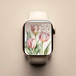 May include: A white Apple Watch with a gold band and a pink floral watch face. The watch face displays the time as 22:20 and the date as SUN 26.