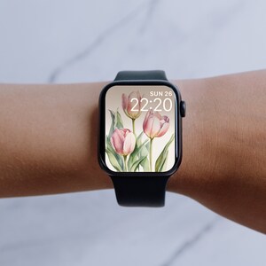 May include: A black smartwatch with a white watch face displaying the date "SUN 26" and the time "22:20". The watch face has a floral design with pink tulips.