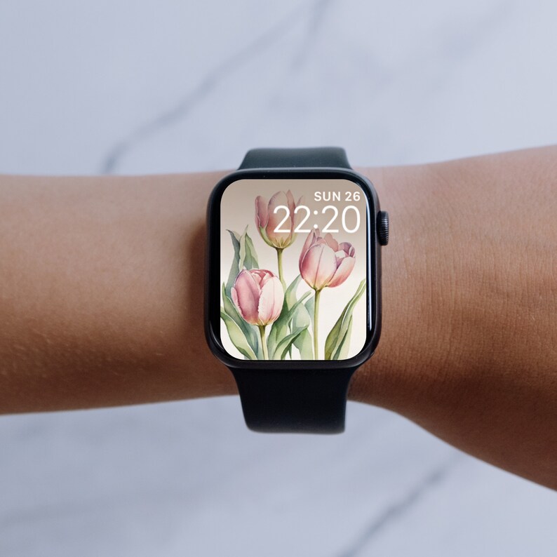 May include: A black smartwatch with a white watch face displaying the date "SUN 26" and the time "22:20". The watch face has a floral design with pink tulips.