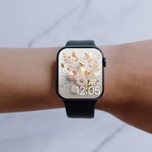 May include: A black smartwatch with a white watch face displaying a floral design with gold accents and the time "SAT 11 12:05".