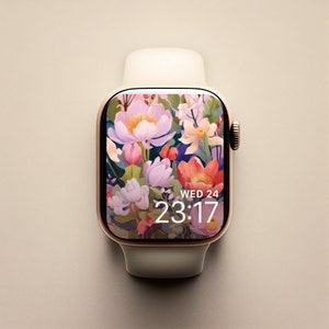 May include: A gold Apple Watch with a white band and a floral watch face. The watch face displays the time as 23:17 and the day as Wed 24.