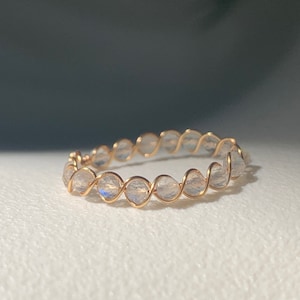 May include: A delicate gold wire ring with a row of clear iridescent stones. The stones are set in a twisted wire design.