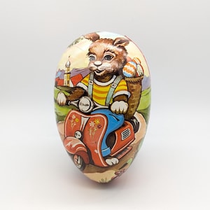 Huevo de Pascua alemán vintage con conejito en moto: contenedor de dulces de papel maché de posguerra, fabricado en Alemania Occidental.