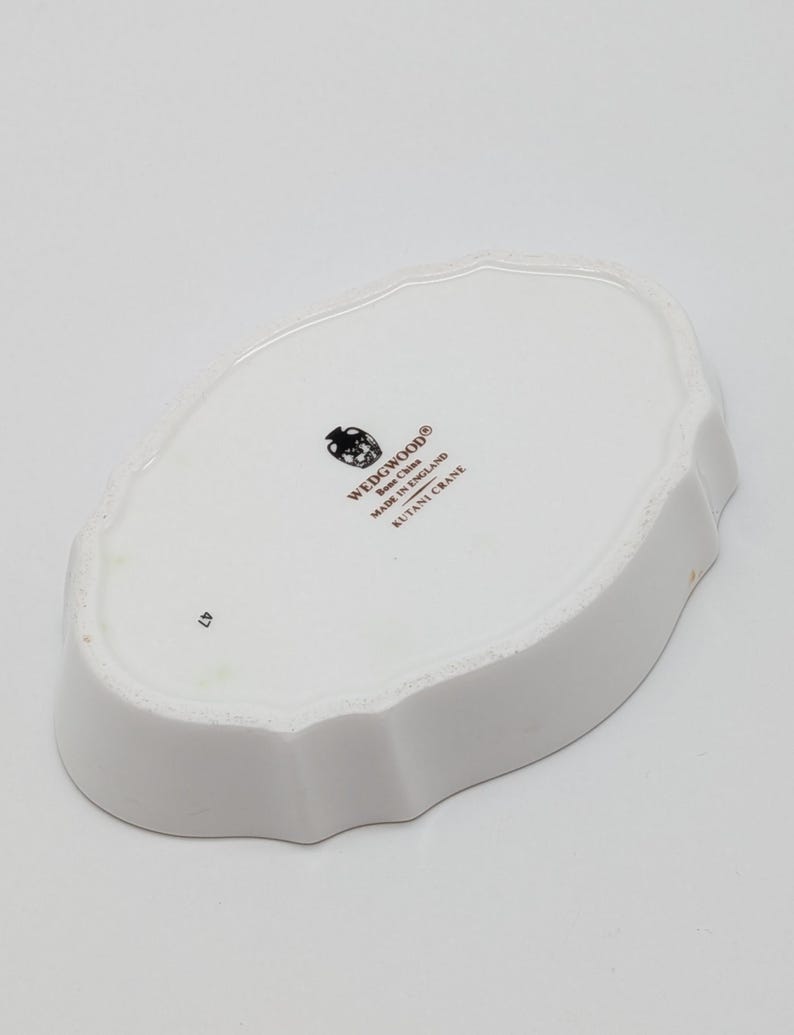 May include: White ceramic dish with a scalloped edge. The underside features the Wedgwood logo, "Bone China Made in England," and "Kutani Crane." The number "47" is printed on the dish.