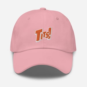 Peut inclure: Une casquette de baseball rose avec un logo brodé orange qui dit "Tits!"