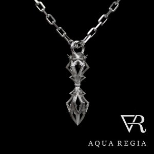 May include: A silver pendant necklace with a detailed, intricate design. The pendant is shaped like a stylized dagger with a pointed tip and a crown-like top. The necklace is on a silver chain.