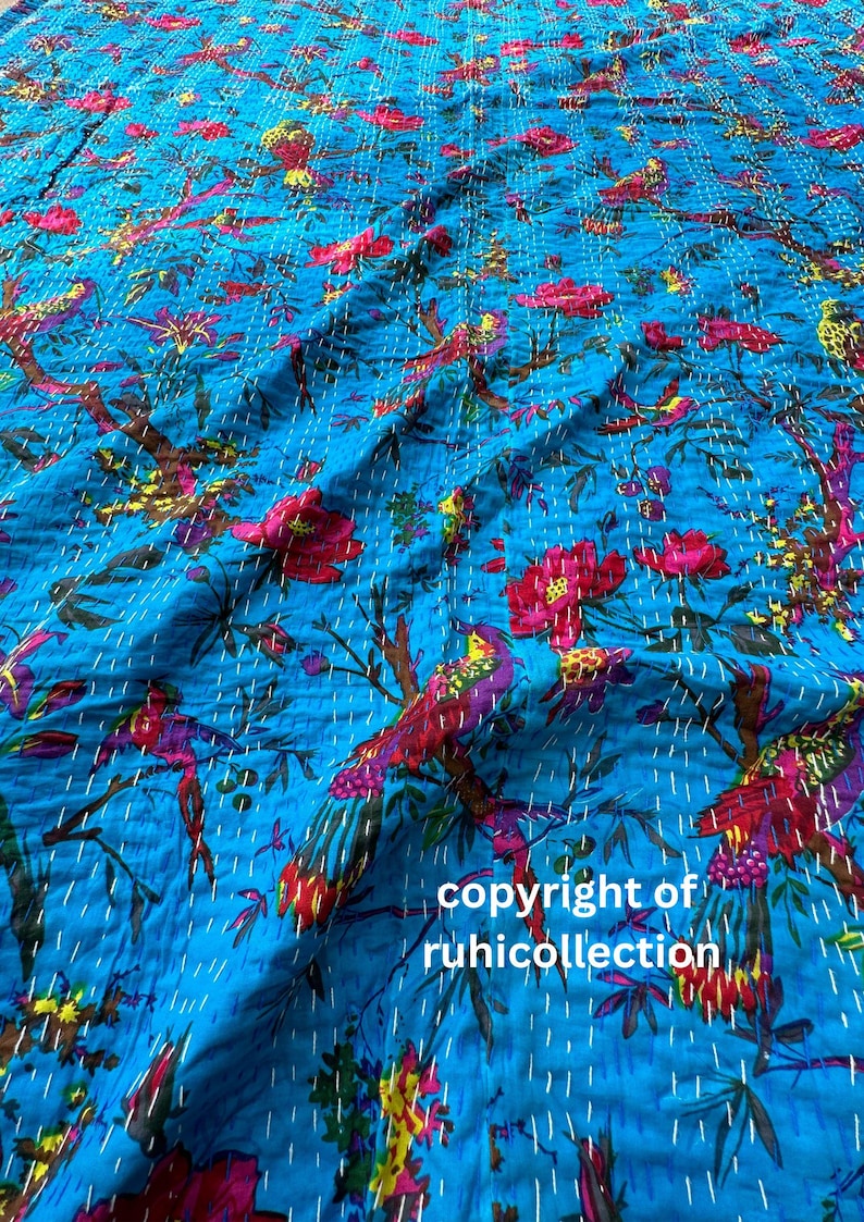 May include: A vibrant blue textile featuring a repeating pattern of birds, flowers, and branches in shades of red, purple, yellow, and green. The design is hand-stitched with white thread. The text "copyright of ruhicollection" is visible.