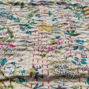 May include: A close-up of a beige fabric with a floral pattern. The fabric is quilted with red and white stitching. The text "copyright of ruhicollection" is visible in the bottom left corner.