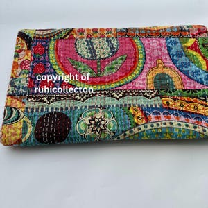 Pu&ograve; includere: Tessuto piegato e colorato con un design patchwork. Il tessuto presenta una variet&agrave; di motivi, tra cui forme floreali e geometriche, nelle tonalit&agrave; del rosa, blu, giallo e verde. Il testo "copyright of ruhicollecton" &egrave; visibile.