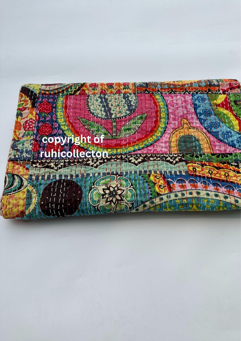 Pu&ograve; includere: Tessuto piegato e colorato con un design patchwork. Il tessuto presenta una variet&agrave; di motivi, tra cui forme floreali e geometriche, nelle tonalit&agrave; del rosa, blu, giallo e verde. Il testo "copyright of ruhicollecton" &egrave; visibile.