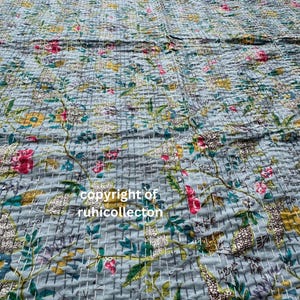 May include: A blue kantha quilt with a floral pattern. The quilt is made of cotton and has a hand-stitched design. The quilt is perfect for adding a touch of bohemian style to your home.