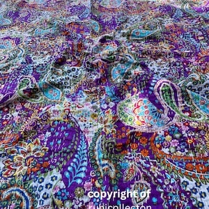 May include: A purple kantha quilt featuring a paisley pattern in shades of blue, green, orange, and pink. The quilt is hand-stitched with white thread and has a white background.