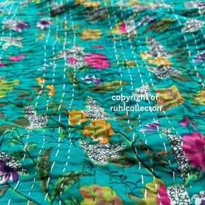 May include: A teal blue kantha quilt with a floral pattern in shades of pink, yellow, and white. The quilt is hand-stitched with white thread and has a textured surface. The text "copyright of, ruhilcollector" is visible in the lower right corner of the image.