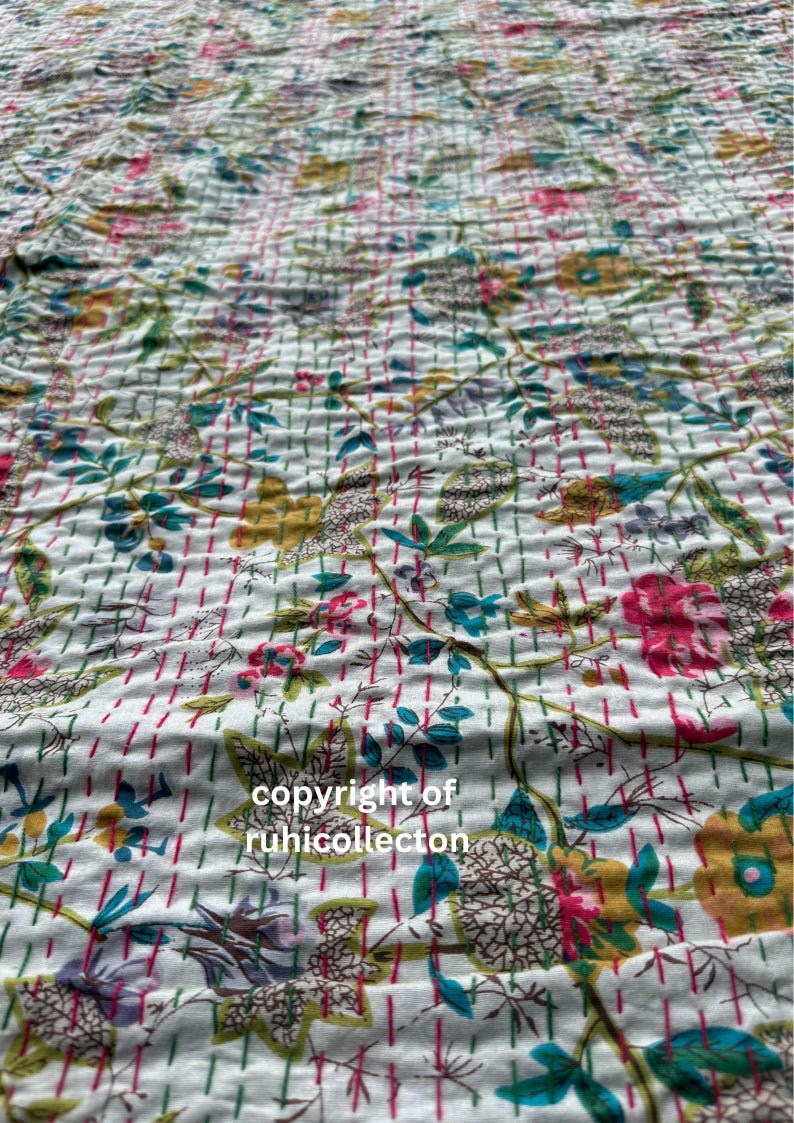 May include: White cotton fabric with a floral pattern in shades of pink, blue, green, and yellow. The fabric has a quilted texture and is decorated with small, evenly spaced lines in pink and green.