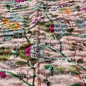 K&ouml;nnte beinhalten: Nahaufnahme eines rosa Stoffes mit Blumenmuster. Der Stoff ist gesteppt mit wei&szlig;em und orangefarbenem Garn. Der Text "copyright of ruhicollecton" ist in der unteren rechten Ecke sichtbar.