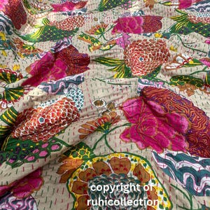 May include: A beige fabric with a colourful floral print. The fabric features a variety of flowers in shades of pink, red, green, yellow, and orange. The fabric is textured and has a slightly distressed look. The text "copyright of ruhicollection" is printed in the bottom right corner of the fabric.