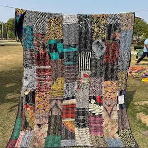 May include: A colourful patchwork quilt, featuring a mix of patterns and shades like black, red, green, and yellow. The quilt is displayed outdoors on a washing line. The text "Ruhicollection" is visible.