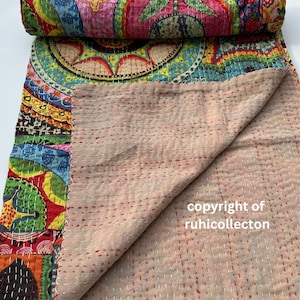 Pu&ograve; includere: Una trapunta colorata arrotolata con un design vibrante. La trapunta presenta un mix di motivi, tra cui cerchi, motivi floreali e forme geometriche nei toni del rosso, blu, giallo e verde. Il retro &egrave; di colore beige.