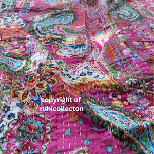 Può includere: Una trapunta in cotone rosa con un motivo floreale e paisley multicolore e ricami kantha a punto dritto bianco. Il tessuto presenta il testo copyright of ruhicollecton stampato in bianco sulla superficie del materiale.