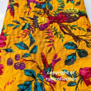 May include: Yellow fabric with a vibrant floral and bird pattern. The design features colorful birds, flowers, and leaves in shades of red, purple, blue, and green. White stitching accents the design. The text "copyright of ruhicollection" is visible.