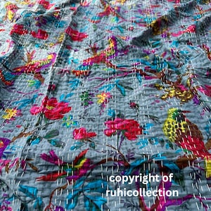 May include: A gray, quilted textile featuring a vibrant floral and bird pattern. The design includes red, pink, yellow, blue, and purple elements. The text "copyright of ruhicollection" is visible. The stitching is white.
