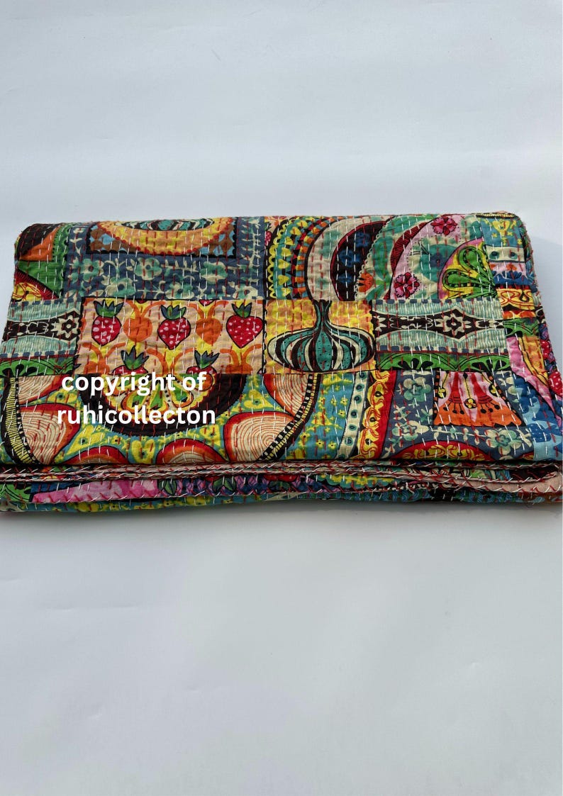 Pu&ograve; includere: Una trapunta piegata e colorata con un design patchwork. La trapunta presenta vari motivi, tra cui fragole e motivi floreali, nelle tonalit&agrave; di blu, verde, giallo e rosso. Il testo "copyright of ruhicollecton" &egrave; visibile.