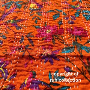May include: Orange fabric with a floral pattern in shades of pink, purple, and teal. The fabric is hand-stitched with white thread. The text "copyright of ruhicollection" is visible.