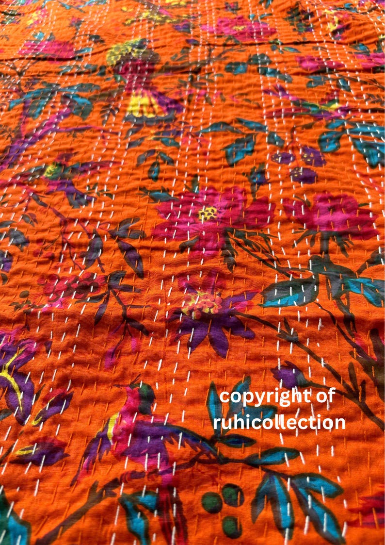 May include: Orange fabric with a floral pattern in shades of pink, purple, and teal. The fabric is hand-stitched with white thread. The text "copyright of ruhicollection" is visible.