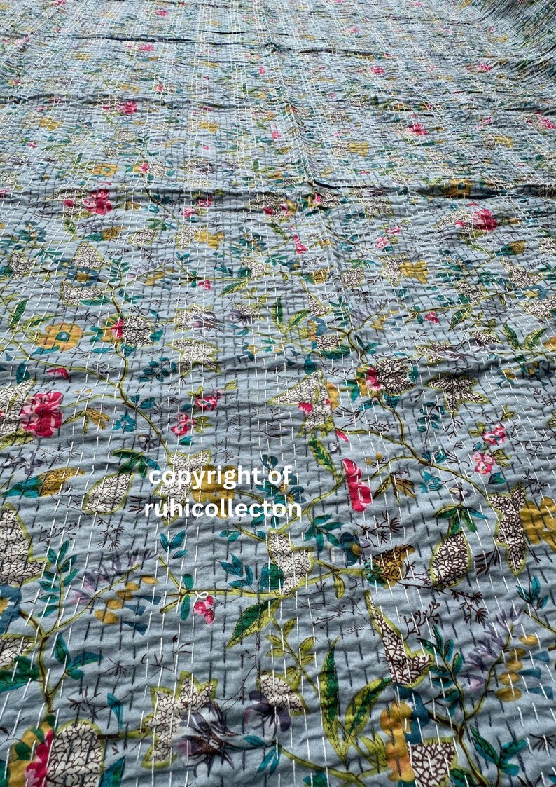 K&ouml;nnte beinhalten: Eine blaue Kantha-Steppdecke mit floralem Muster. Die Steppdecke ist aus Baumwolle und hat ein handgesticktes Design. Die Steppdecke ist perfekt, um Ihrem Zuhause einen Hauch von Boho-Stil zu verleihen.