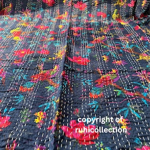 May include: Dark blue floral quilt with a vibrant pattern of red, yellow, and blue flowers and birds. The quilt is hand-stitched with white thread, creating a textured effect. The text "copyright of ruhicollection" is visible.