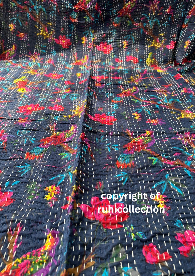 May include: Dark blue floral quilt with a vibrant pattern of red, yellow, and blue flowers and birds. The quilt is hand-stitched with white thread, creating a textured effect. The text "copyright of ruhicollection" is visible.