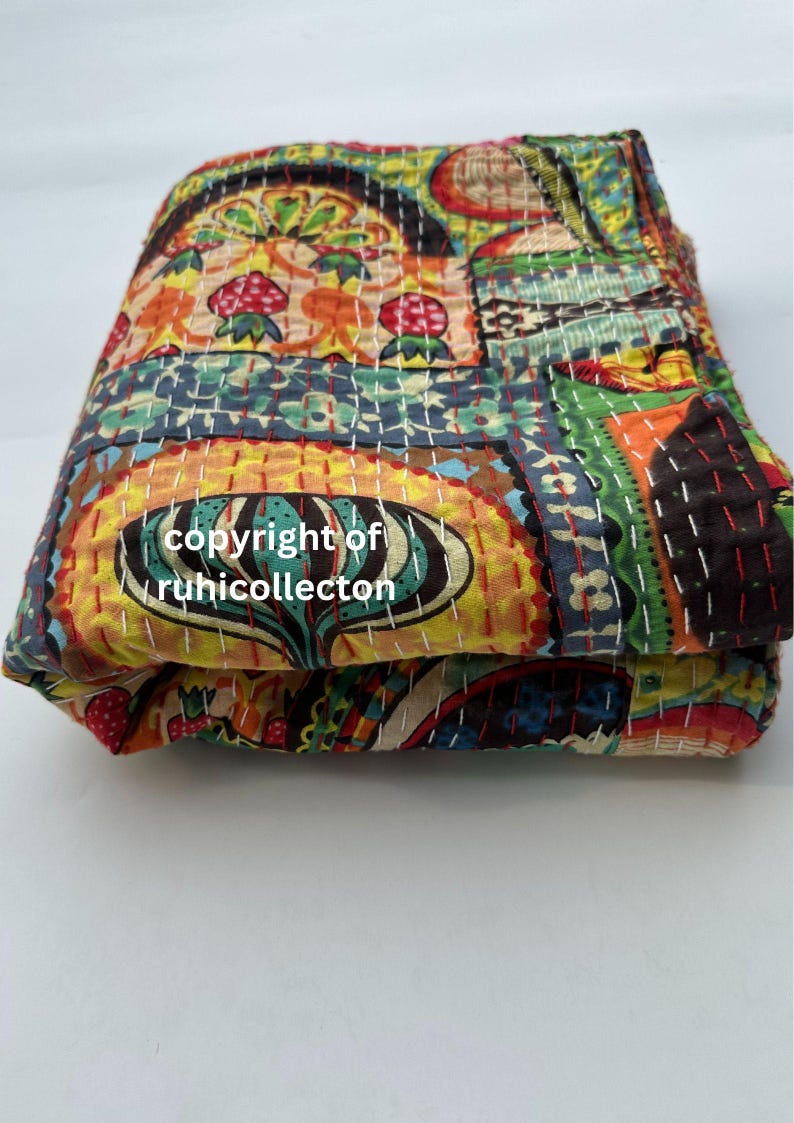 Pu&ograve; includere: Trapunta piegata e colorata con un design patchwork. La trapunta presenta una variet&agrave; di motivi e colori, tra cui arancione, giallo, blu e verde. La trapunta &egrave; cucita con filo bianco e presenta il testo "copyright of ruhicollecton".