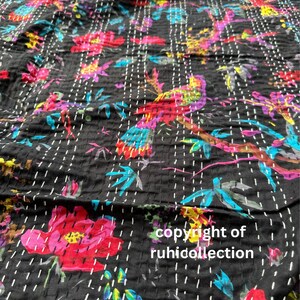 May include: Black fabric with a colorful floral and bird pattern. The design features red, pink, blue, and yellow flowers and birds on branches. The fabric is stitched with white thread. The text "copyright of ruhicollection" is visible.