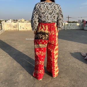 May include: A pair of red and cream patchwork pants with a paisley print. The pants have a wide leg and are made from a soft, comfortable fabric.