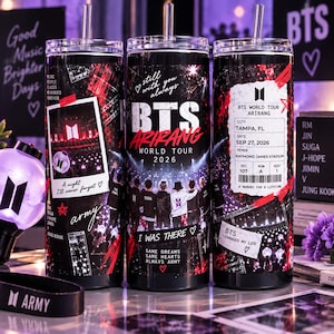 May include: Three black cylindrical tumblers with lids and straws, featuring BTS World Tour Arirang 2026 graphics, concert photos, a mock ticket for Tampa, FL, and text including Still with you always, I was there, and Same dreams same hearts.