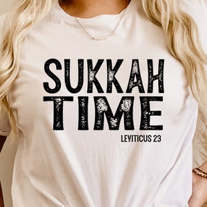 Może przedstawiać: Biała koszulka z czarnym napisem "Sukkah Time" i "Księga Kapłańska 23".