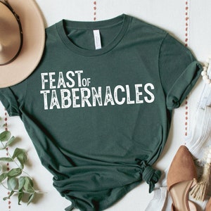 Może przedstawiać: Zielony T-shirt z napisem "FEAST OF TABERNACLES" w białym kolorze. Koszulka wykonana jest z miękkiego, wygodnego materiału i ma luźny krój.