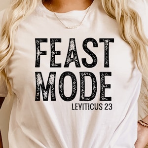 Może przedstawiać: Biała koszulka z czarnym napisem "Feast Mode" i "Leviticus 23".