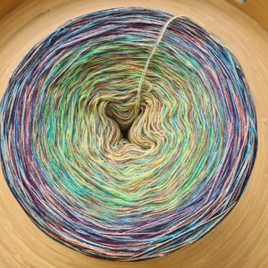 May include: A tightly wound ball of yarn with a gradient of colors, including blue, green, yellow, and purple. The yarn is arranged in concentric circles, with a strand extending from the center. The yarn is likely for knitting or crocheting projects.