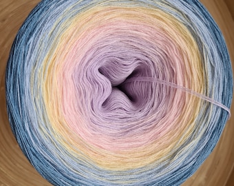 May include: A tightly wound ball of yarn with a gradient of colors. The yarn transitions from a deep blue to yellow, pink, and lavender in a circular pattern. A single strand of yarn extends from the center.