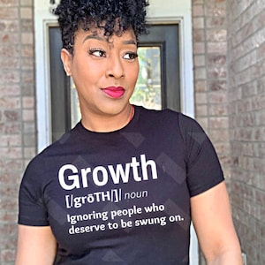 May include: Black crew neck t-shirt with the word "Growth" in white, its pronunciation and definition. The shirt also features the phrase "Ignoring people who deserve to be swung on."
