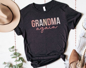 May include: A black heather grey t-shirt with the text "GRANDMA again" in pink and white lettering.