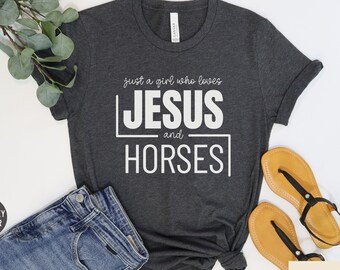 May include: Dark grey heather t-shirt with the text "Just a girl who loves Jesus and Horses" in white.