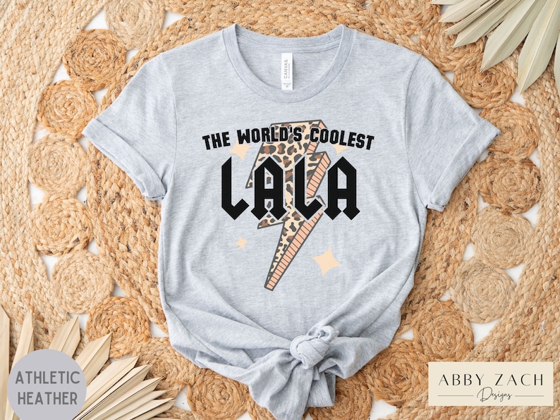 May include: A gray t-shirt with a black lightning bolt graphic and the text "The World's Coolest Lala" in black. The lightning bolt is filled with a leopard print pattern.