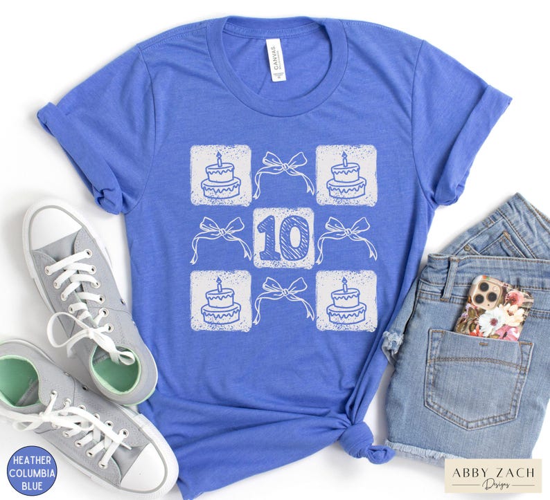 Peut inclure: Un t-shirt bleu avec un motif blanc repr&eacute;sentant un g&acirc;teau d'anniversaire et le chiffre 10. Le motif est r&eacute;p&eacute;t&eacute; en grille.